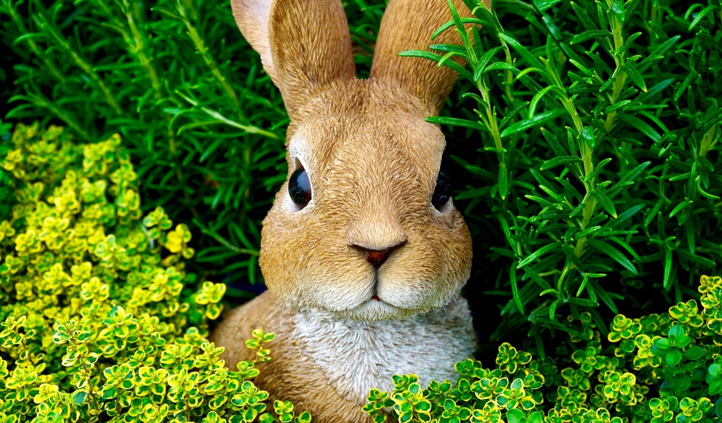 Статуэтка кролика в зеленой траве 