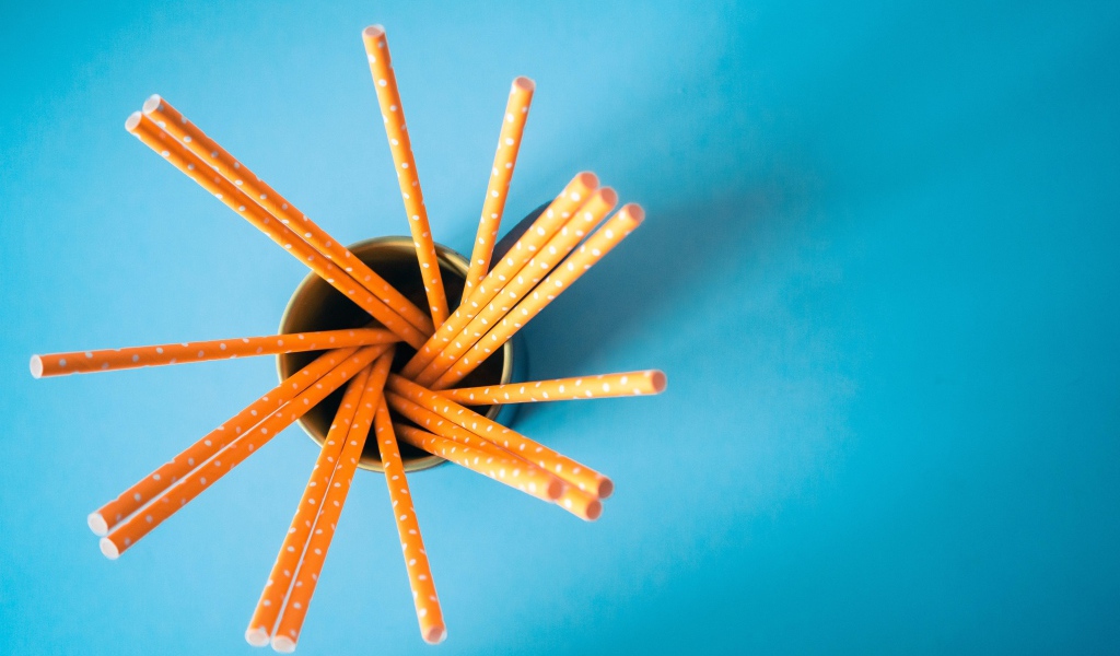 Трубочки в стакане на голубом столе