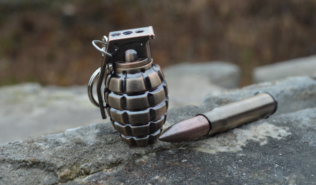 Боевая граната с патроном лежат на камне 