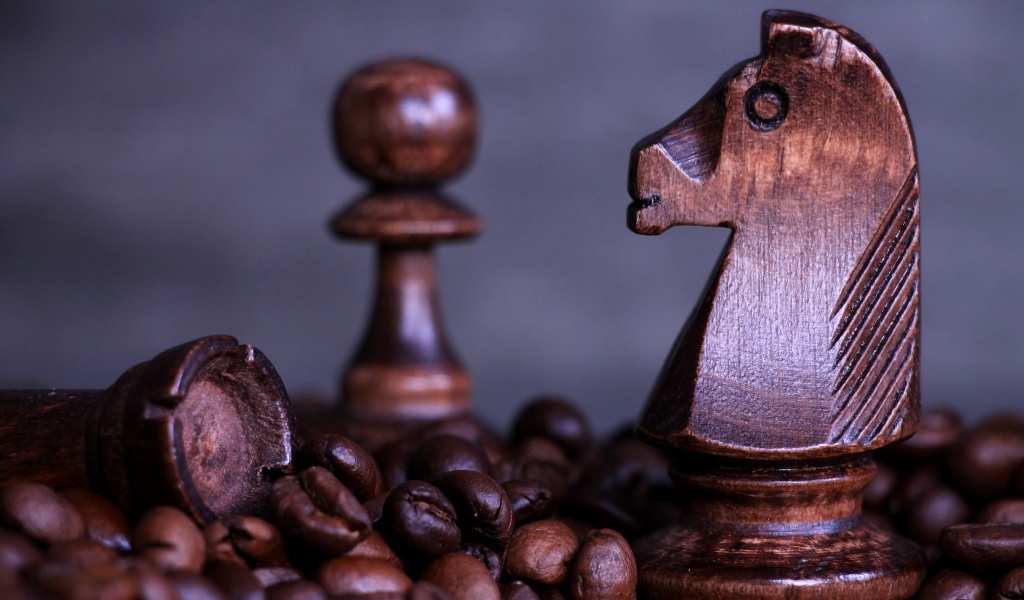 Деревянные шахматные фигуры стоят на кофейных зернах 