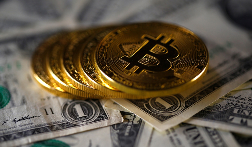 Монеты Биткоин лежат на купюрах по одному доллару