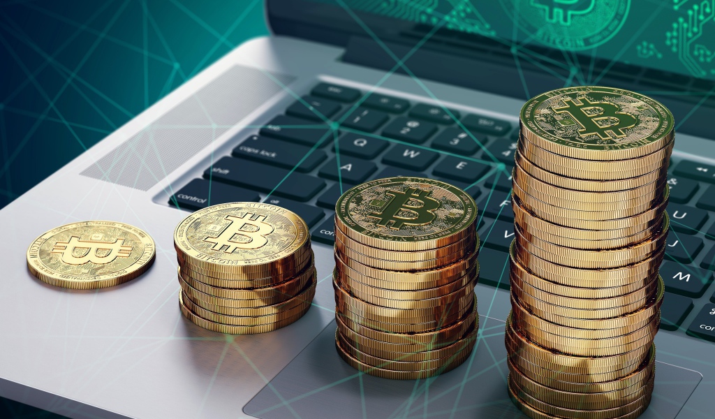 Золотые монеты Биткоин лежат на ноутбуке