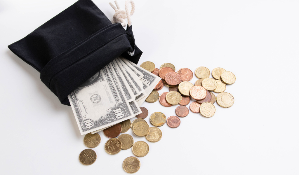 Кошелек с монетами и долларами на белом фоне