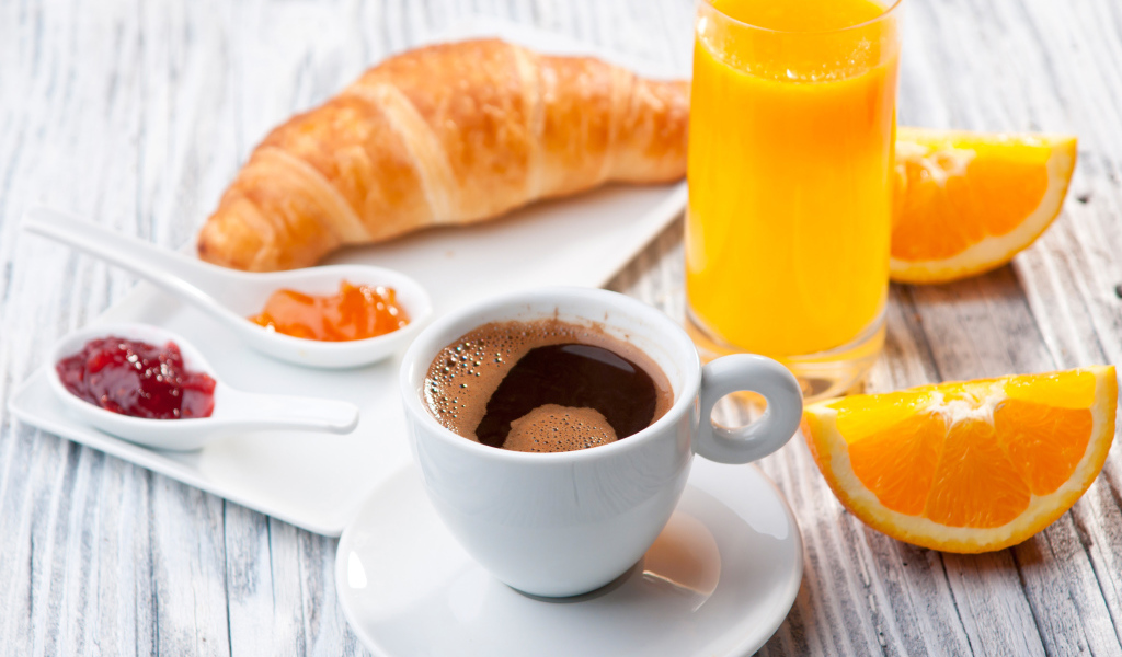 Чашка кофе на столе с соком и круассаном