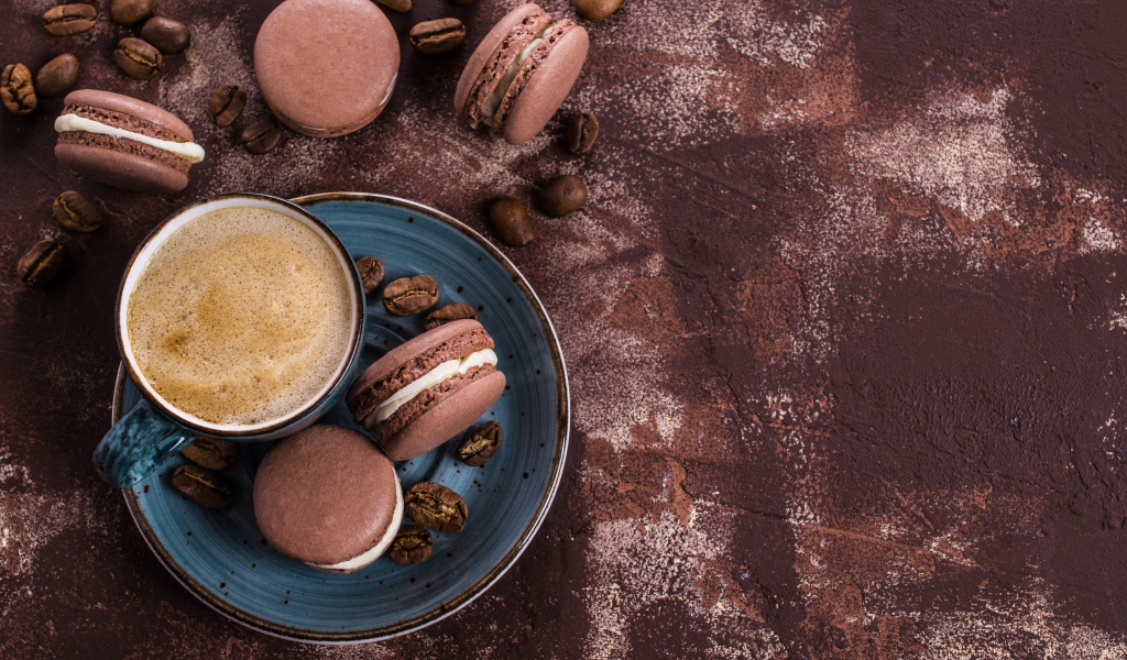 Чашка кофе с шоколадными макарунами на столе