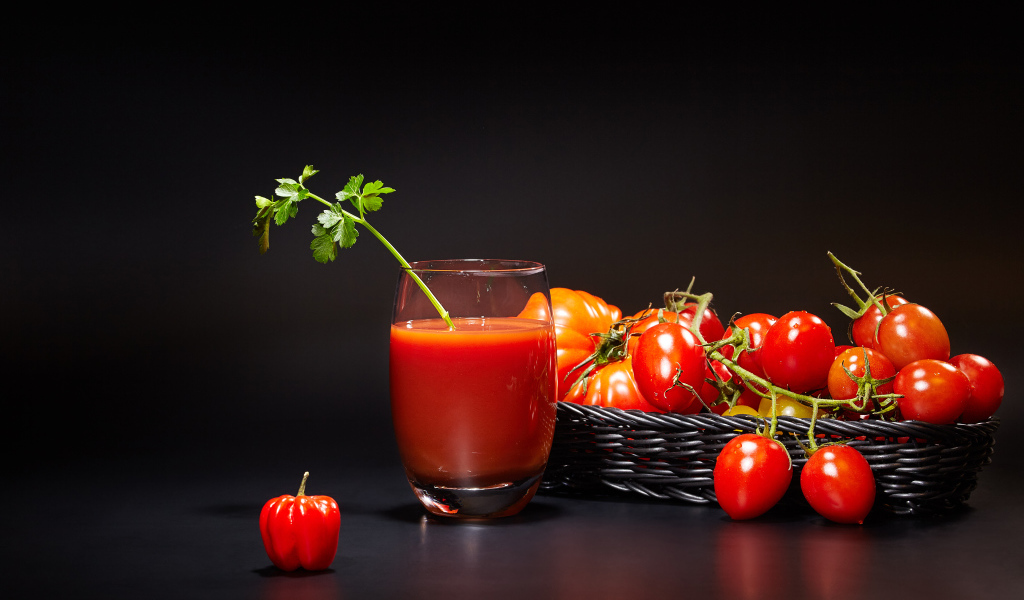 Стакан томатного сока на столе с помидорами