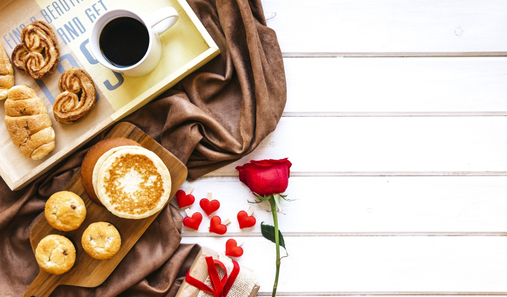 Выпечка на столе с кофе, подарком и красной розой