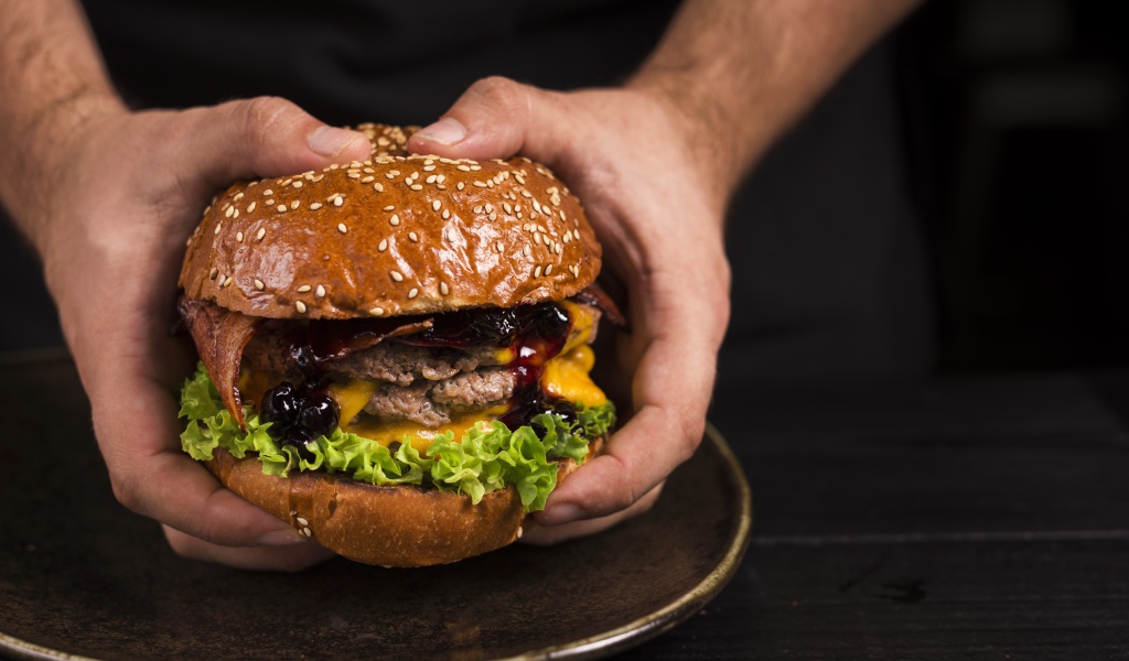 Большой сочный гамбургер в руках