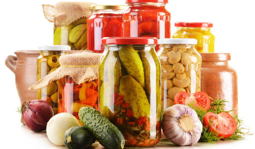 Консервация в банках на белом фоне с овощами