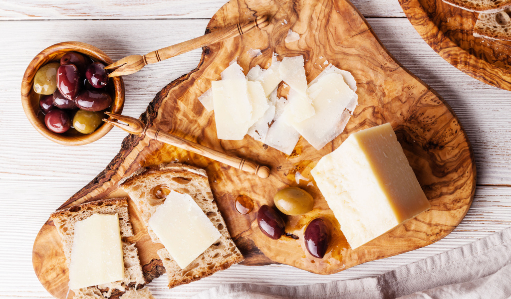 Сыр на доске с хлебом и и оливками