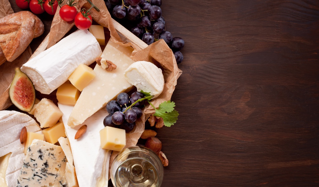 Сыр на столе с виноградом, инжиром и помидорами