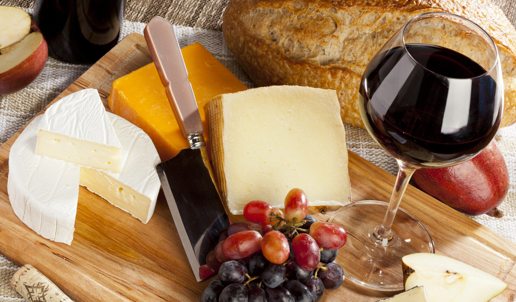 Сыр на столе с виноградом и вином