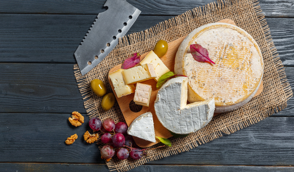 Сыр с плесенью на столе с орехами и виноградом 