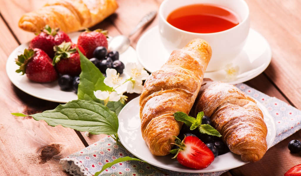 Круассаны на столе с ягодами и чашкой чая