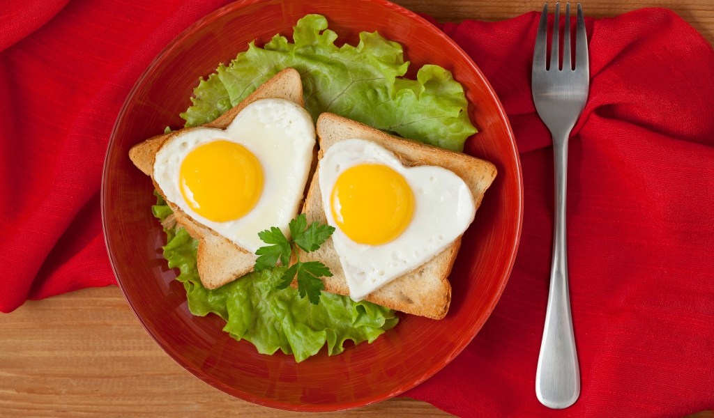 Гренки с яичницей на тарелке с листьями салата 