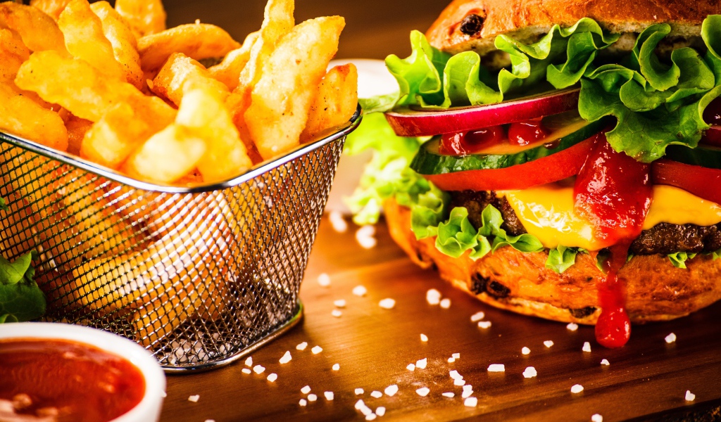 Аппетитный сочный гамбургер на доске с картошкой фри и соусом