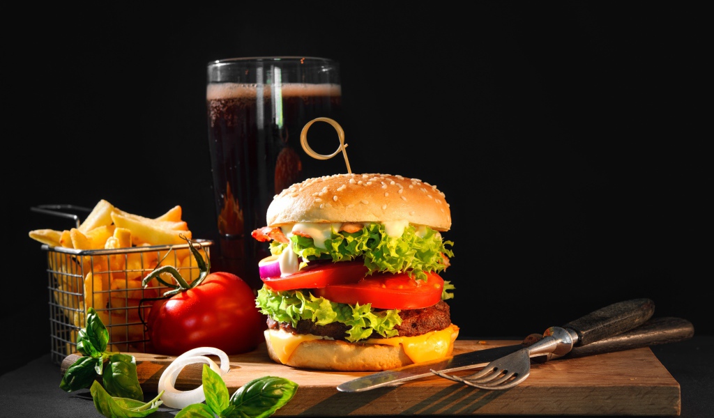 Вкусный аппетитный гамбургер на столе с пивом и картофелем фри