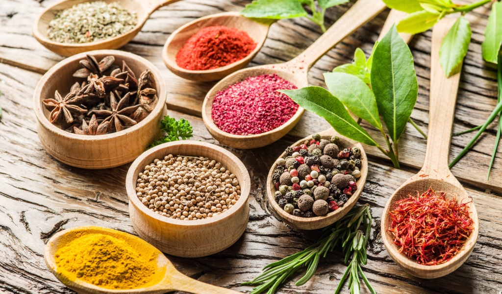 Разные специи в деревянных ложках на столе 