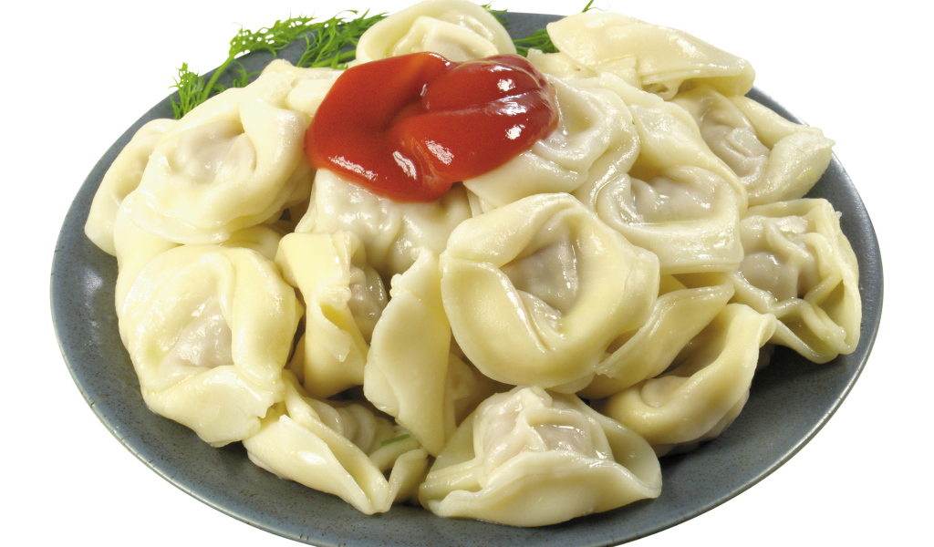 Пельмени в тарелке с кетчупом на белом фоне