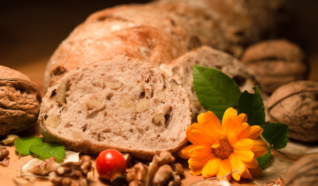 Свежий хлеб с грецкими орехами и цветами календулы на столе
