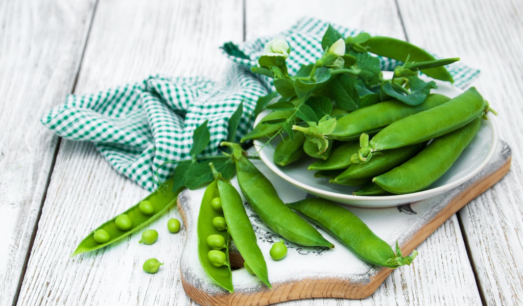 Свежий зеленый горох на столе с полотенцем