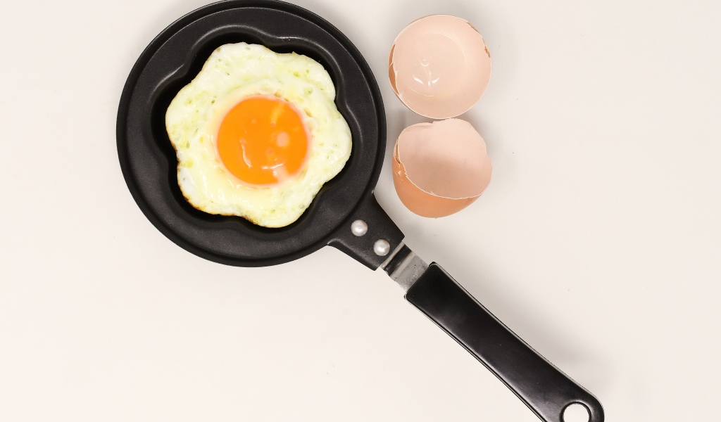 Яичница на сковороде на сером фоне со скорлупой
