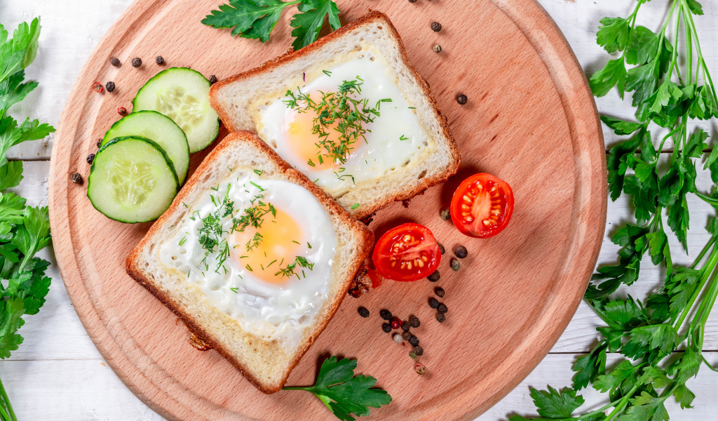 Яичница в хлебе на доске с помидорами, огурцами и петрушкой