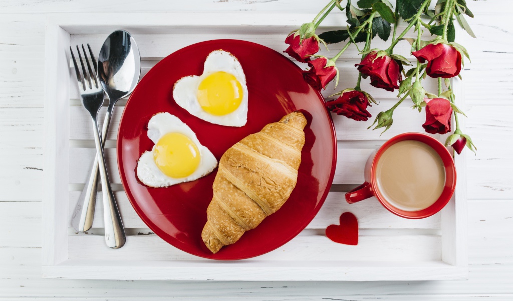 Яичница с круассаном на красной тарелке на столе букетом роз и чашкой какао