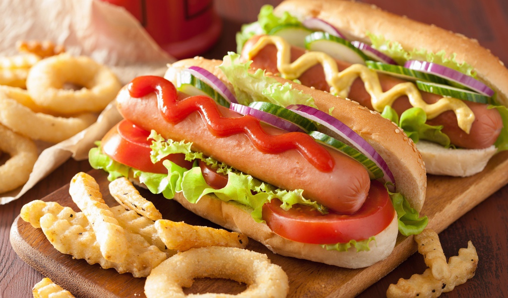 Хотдоги с овощами на разделочной доске с картофелем фри