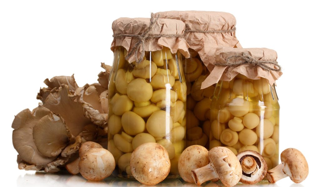 Маринованные шампиньоны в банках на белом фоне со свежими