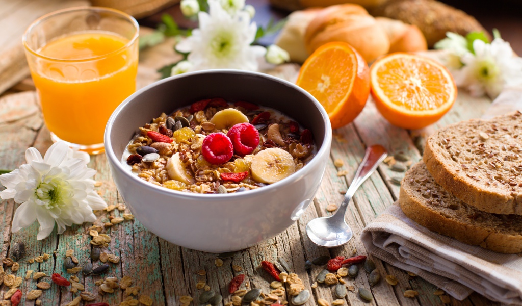 Мюсли в миске с молоком на завтрак с соком и апельсинами 