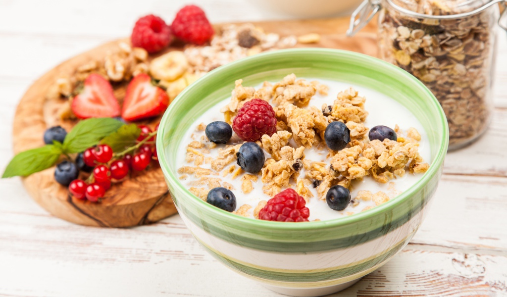 Мюсли с молоком и ягодами на столе к завтраку