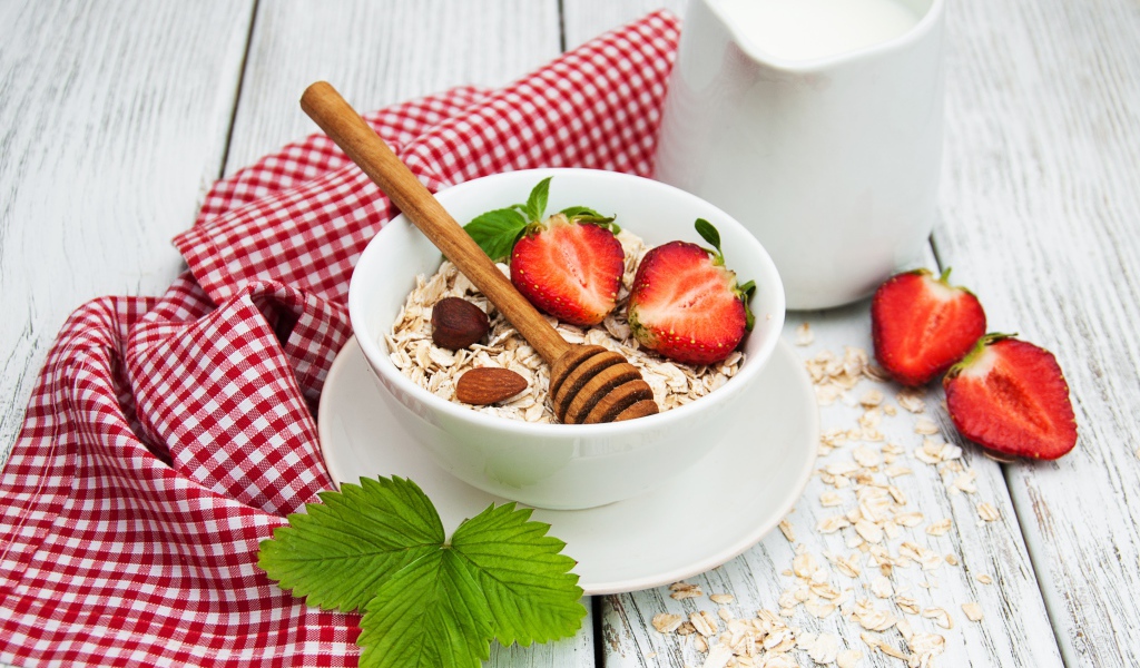 Овсяная каша на столе с молоком и клубникой