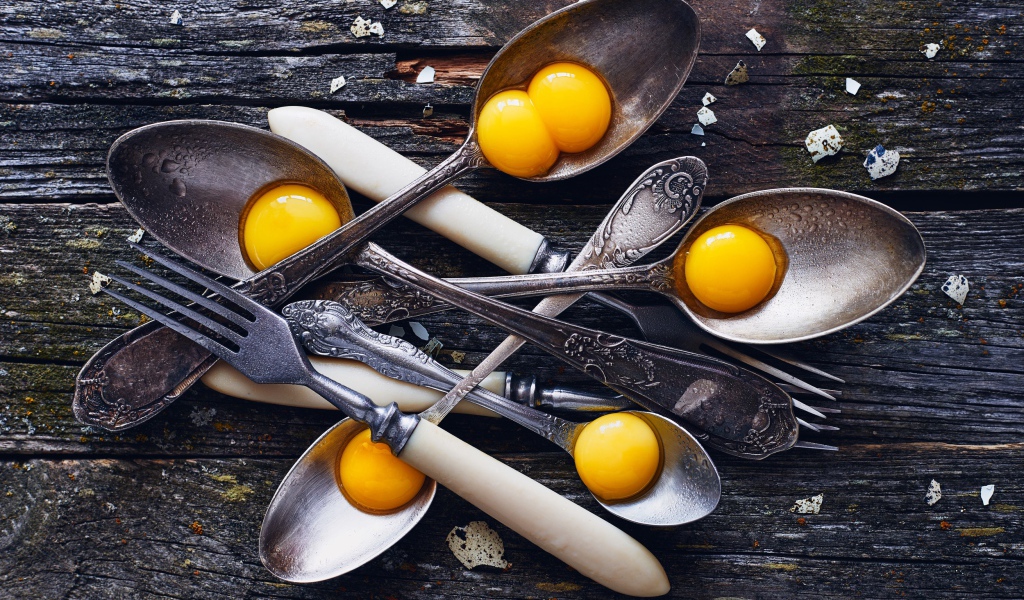 Старые ложки с желтками на деревянном столе