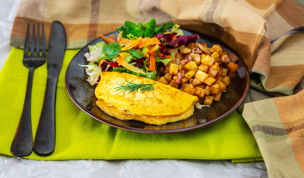 Омлет на тарелке с салатом и овощами