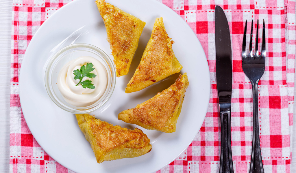 Блинчики со сметаной на столе со столовыми приборами 