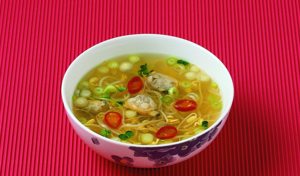 Тарелка супа с морепродуктами на красном фоне