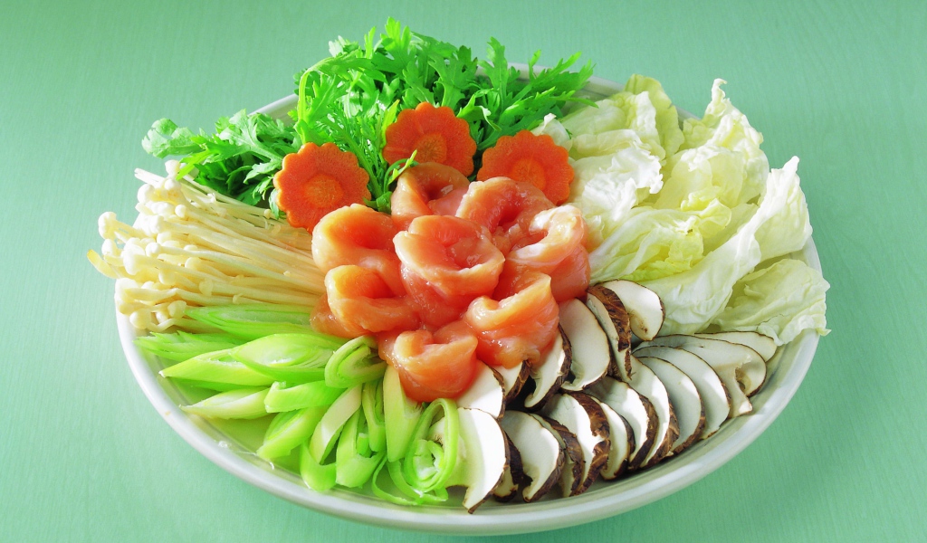 Тарелка с овощами и красной рыбой на зеленом фоне