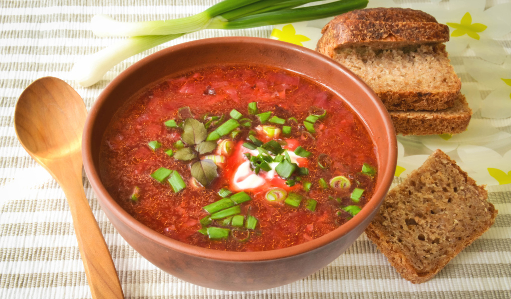 Красный борщ с луком на столе с хлебом 