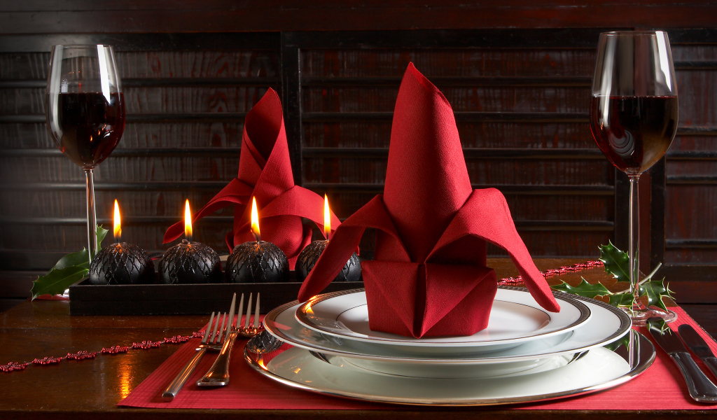 Red napkin on a plate on the table with glasses of wine and candles