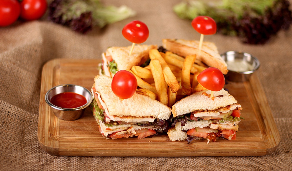 Сэндвичи на доске с картофелем фри и соусом