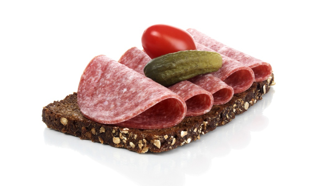 Бутерброд с черным хлебом, колбасой, соленым огурцом и помидором на белом фоне