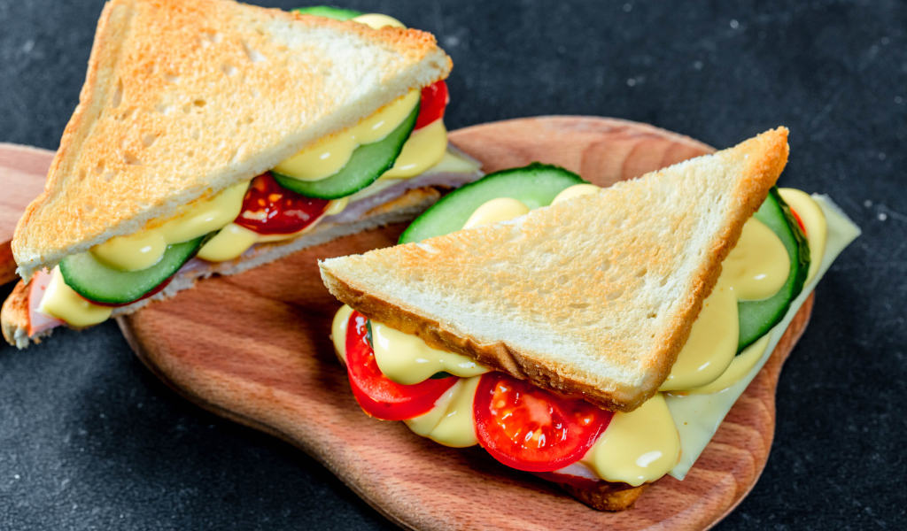 Сэндвич с сыром, помидорами и огурцами на столе