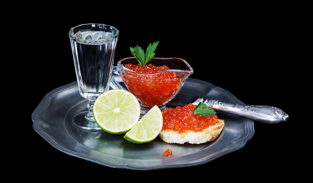 Бутерброды с красной икрой на подносе с рюмкой водки и лаймом