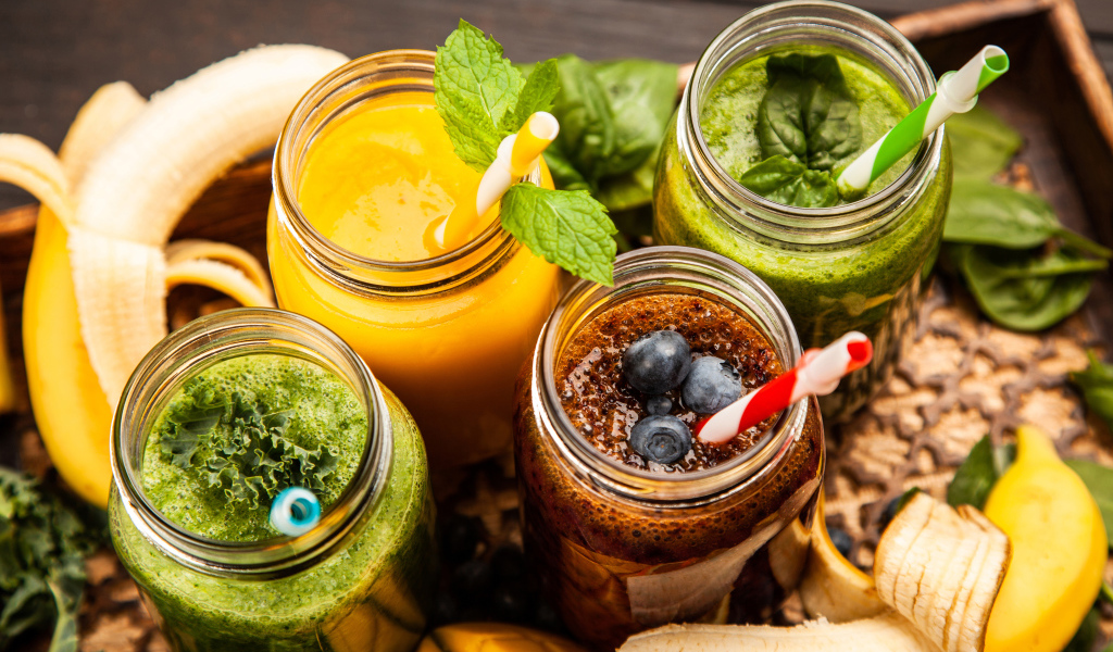 Банки со смузи на столе с бананами