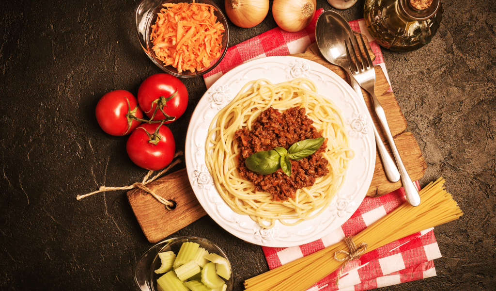 Спагетти с фаршем на столе с овощами
