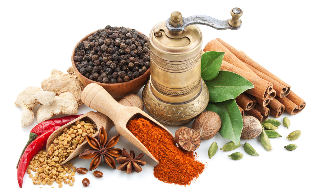 Пряные специи на столе с мельницей на белом фоне