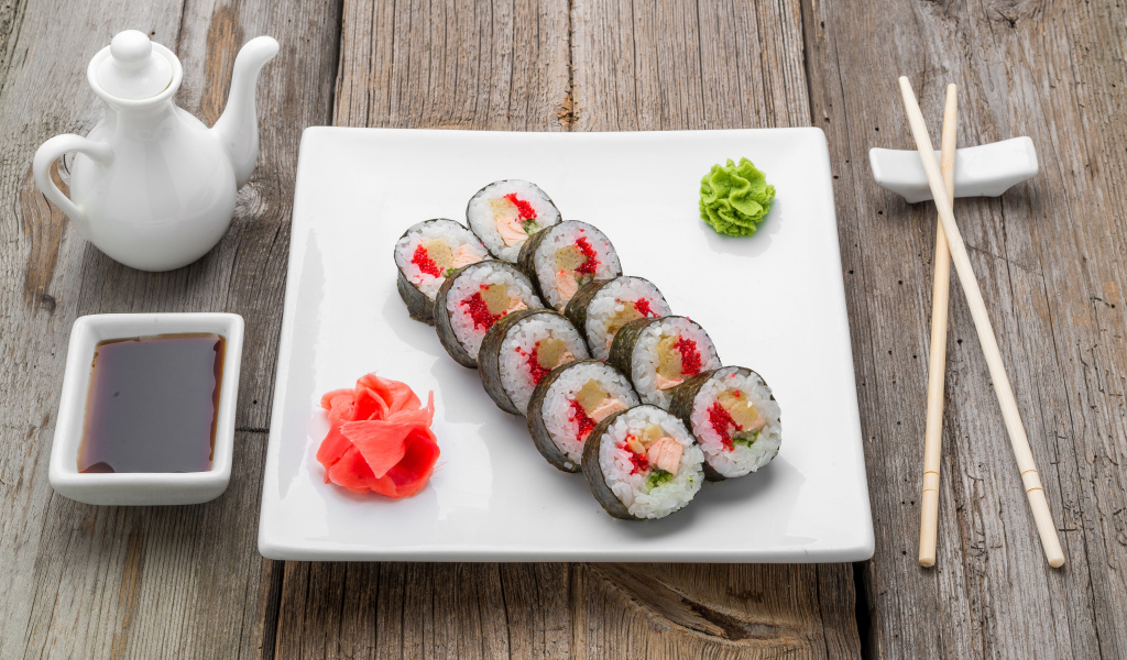 Суши на большой белой тарелке с соусом васаби и имбирем на столе соевым соусом