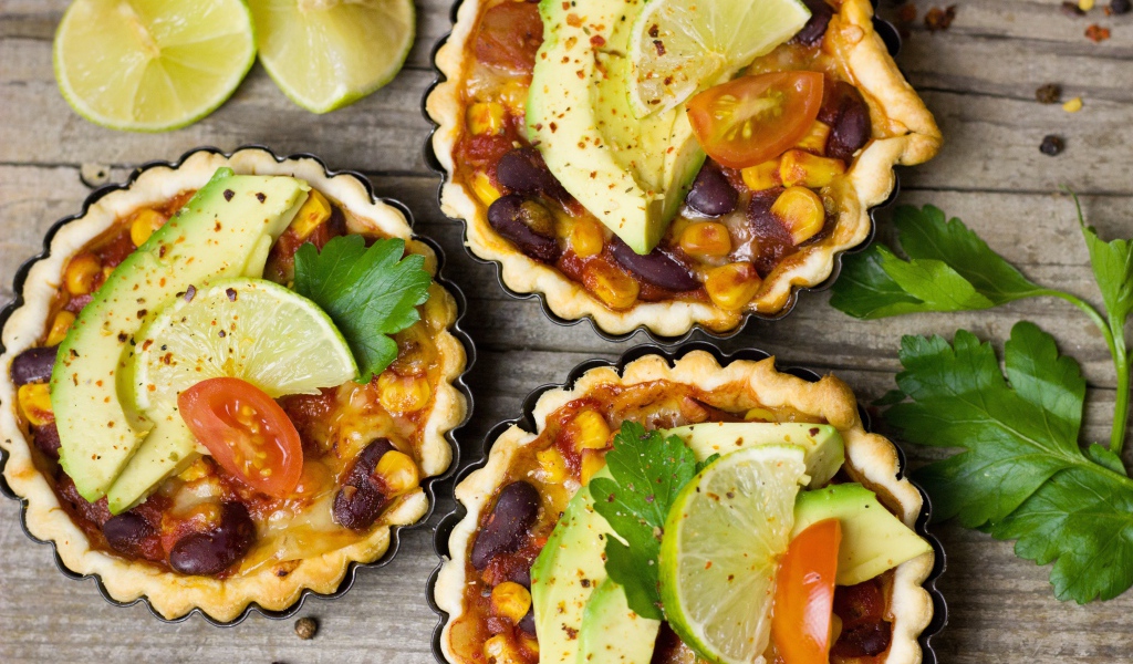 Тарталетки с блюдом, кусочками авокадо и лайма на столе