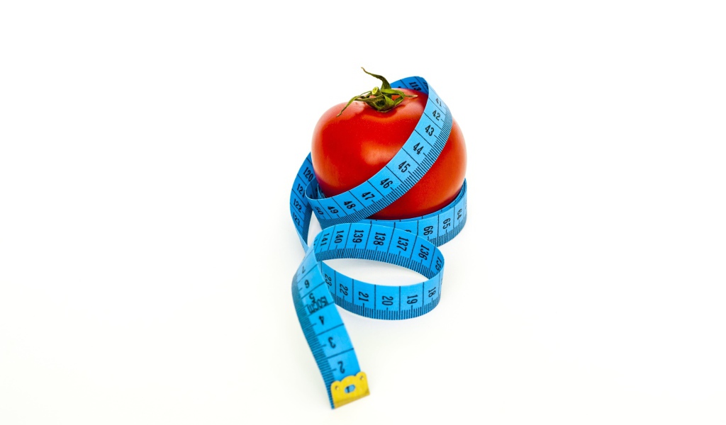 Помидор с голубым сантиметром на белом фоне